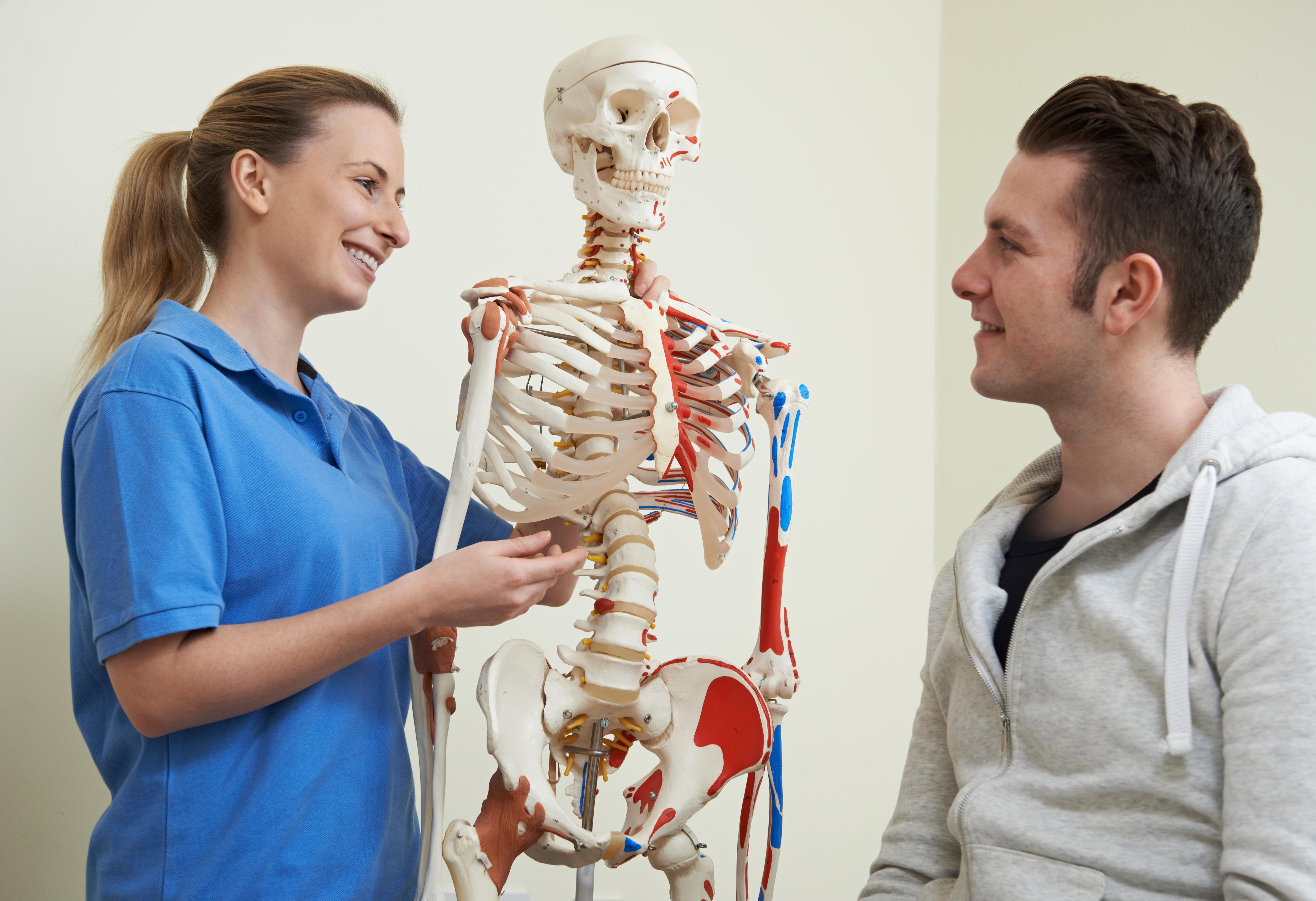 A photo of an osteopath explaining treatment to a patient